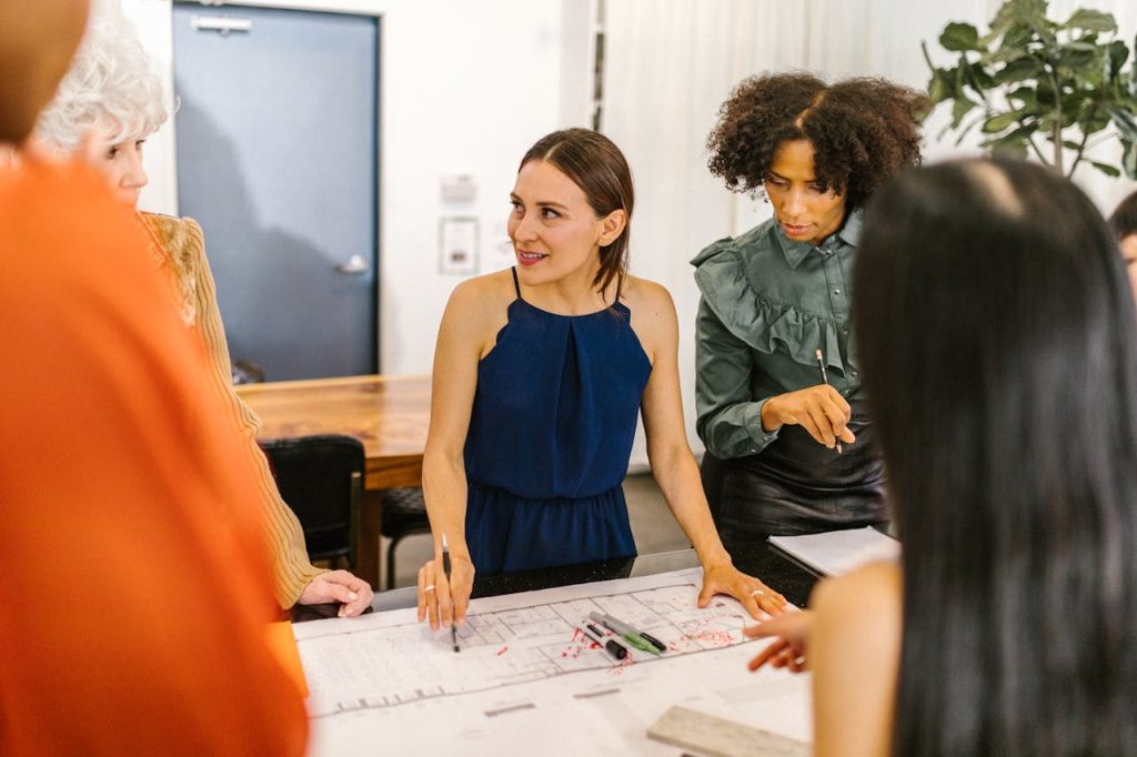 Diverse group of women collaborating in a modern office setting, fostering teamwork and empowerment.